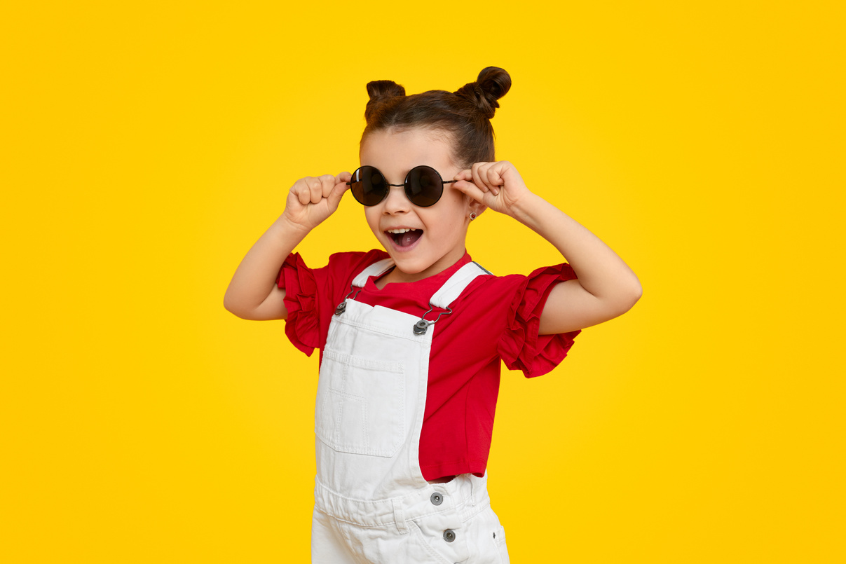 Cheerful kid model trying on stylish sunglasses